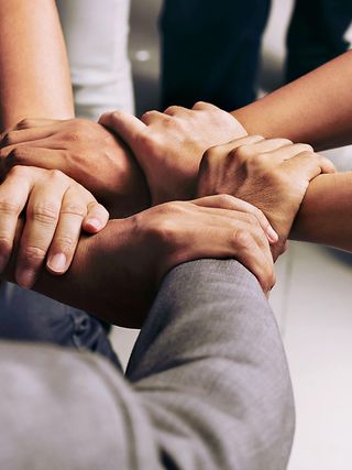 Close-up of five different hands holding each other's wrists, forming a circle