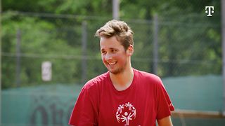 Tennisspieler Louis Kleemeyer lachend in einem roten T-Shirt auf einem Tennisplatz.