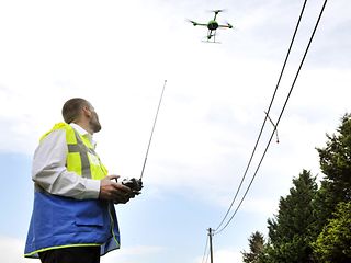 Telekom Mitarbeiter steuert kleinen Helikopter mit einer Fernsteuerung.