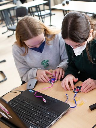 Drei Schülerinnen programmieren eine künstliche Intelligenz mithilfe des Mikro-Computers Calliope mini.