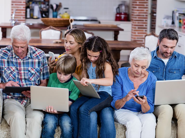 Eine sechsköpfige Familie sitzen zusammengedrängt auf dem Sofa. 