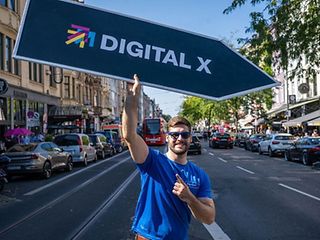 A man carries a sign leading to Digital X.