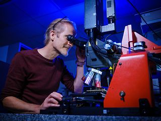 An employee looking into a microscope.