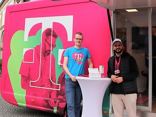 Die beiden Azubis an einem Stehtisch vor dem Telekom Truck