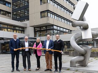 Die genannten Personen stehen vor dem Rathaus der Stadt Sindelfingen und halten gemeinsam eine Speedpipe in den Händen.