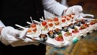 A waiter holds a tray with appetisers.