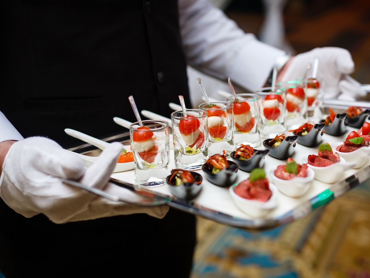 A waiter holds a tray with appetisers.