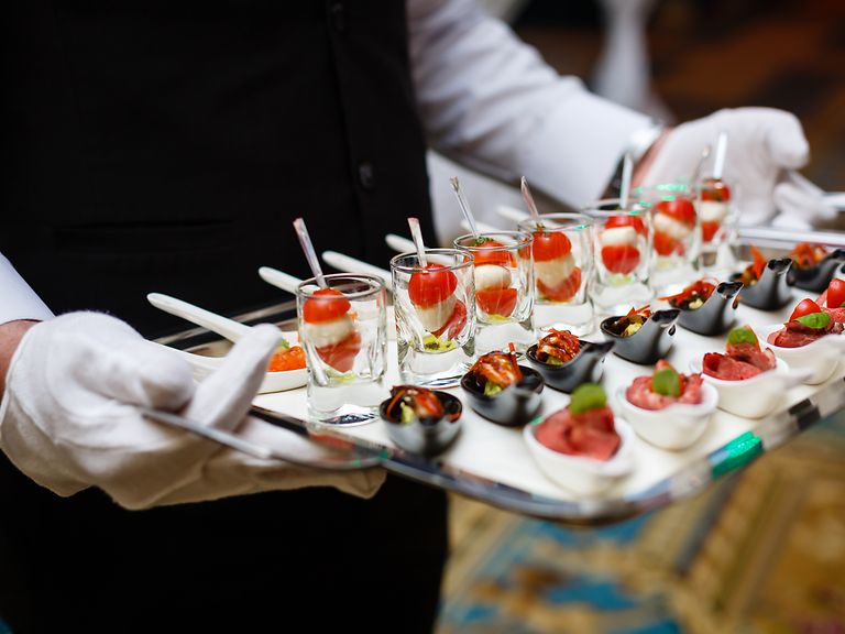 A waiter holds a tray with appetisers.