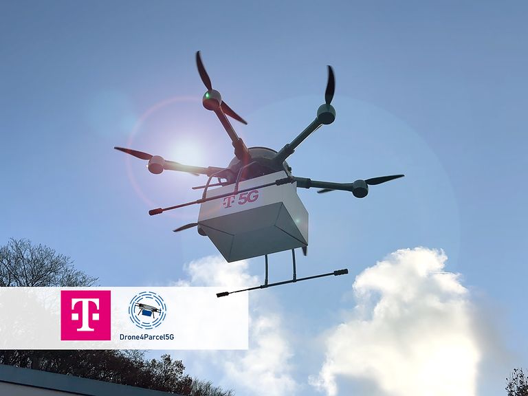 Eine Flugdrohne transportiert am Himmel ein weißes Paket mit der Aufschrift „T5G“.