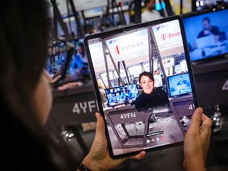 Eine Frau hält ein Tablet mit einer Augmented Reality Applikation. Darauf zu sehen der Avatar einer jungen Frau.