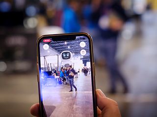 Nahaufnahme eines Smartphones mit laufender Augmented Reality App. Ein digitaler Roboter wird über das Realbild geblendet.