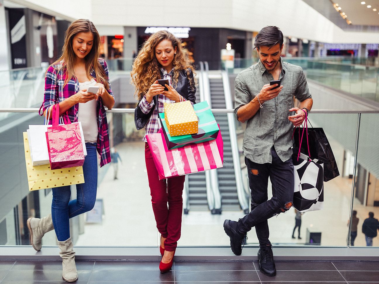 People with cell phones and shopping bags.