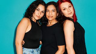Three women stand together and look at the camera