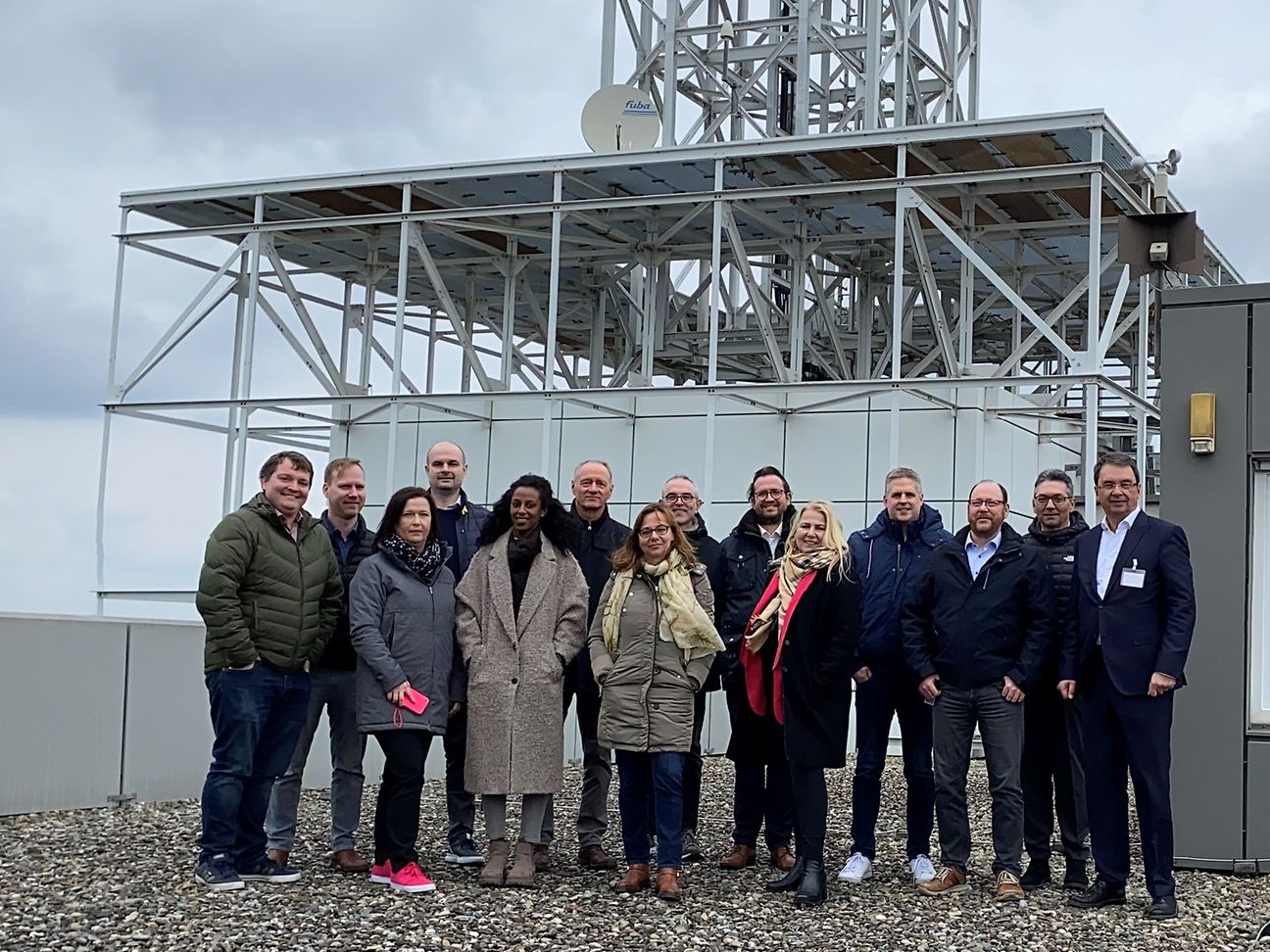 Die Besuchergruppe steht auf dem Dach des Gebäudes vor der Antenne.