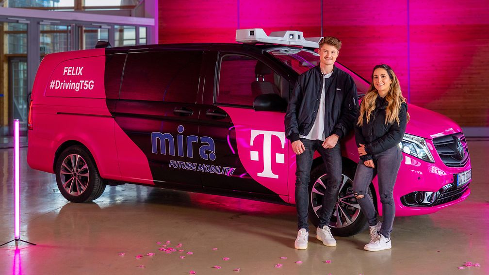 Vor einem magentafarbenen Mini-Bus mit Technik-Aufbau stehen die Content-Creator Lisa Yasmin und Felix von der Laden. 
