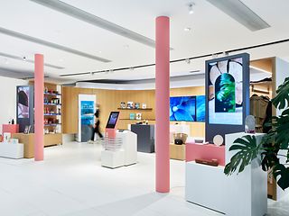 Der Retail Bereich der T Gallery mit großem Regal, Kühlschrank und großen Screens für Informationen.