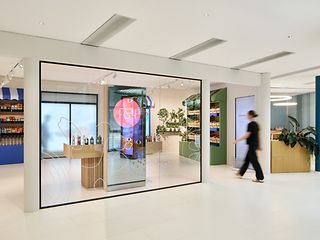 Der Retail Bereich der T Gallery mit großem Regal, Kühlschrank und großen Screens für Informationen.
