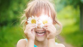 Girl holding flowers to her eyes.