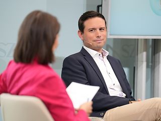 Interview situation: woman with brunette hair from behind and Benjamin Springub from the front.