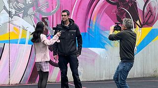 Eine junge Influencerin interviewt einen Auszubildenden von der Telekom auf einem Basketballplatz