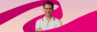 A man has his arms crossed and smiles into the camera