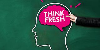 A male hand holds a sign as a brain with the inscription Think fresh.