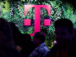 The Deutsche Telekom “T” in magenta in front of a green natur-like background.