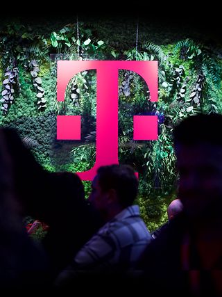 The Deutsche Telekom “T” in magenta in front of a green natur-like background.