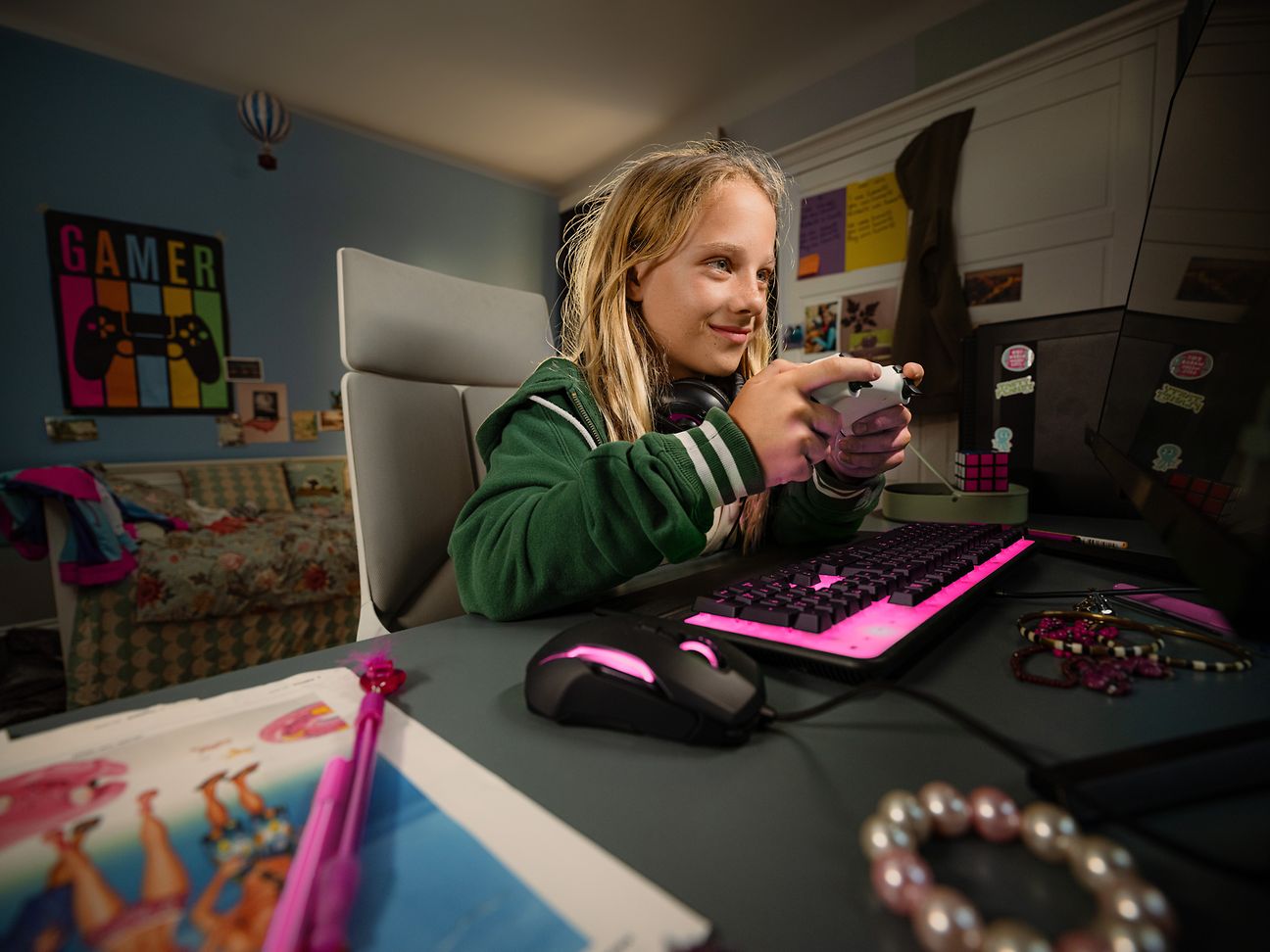 Ein Kind sitzt am Schreibtisch und spielt Computerspiele. Tastatur und Maus Leuchten in Magenta.