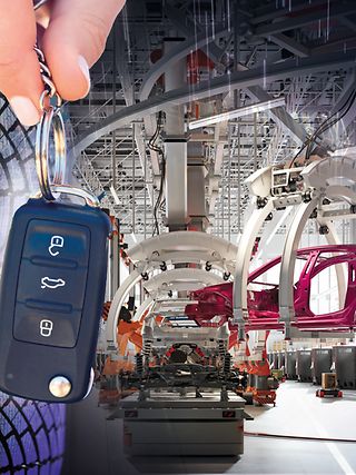 A car key and a vehicle on the assembly line in production.