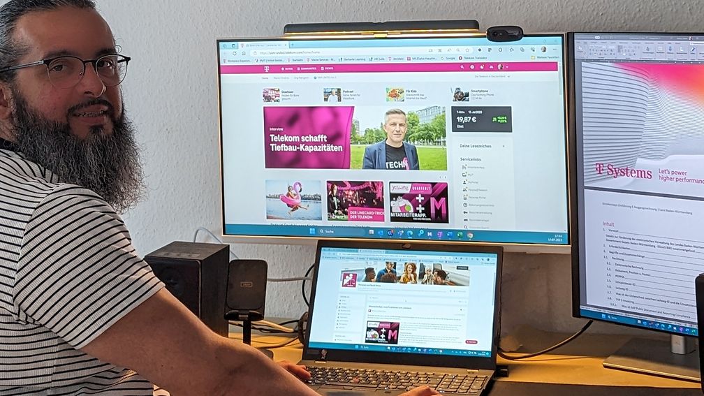  Hasan Kökcü stands in front of his desk with his laptop and two large screens