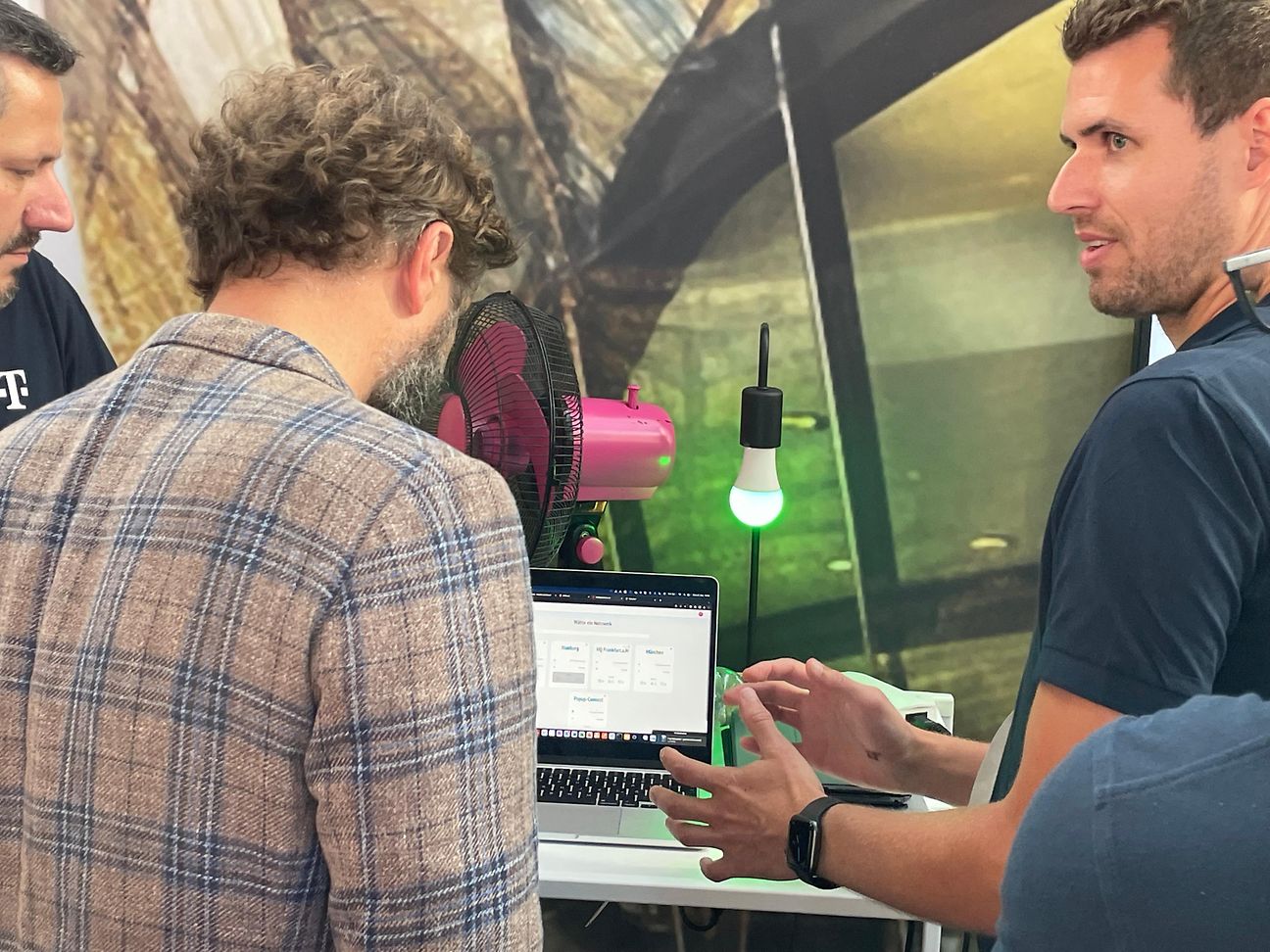 A man explains something to others on a monitor