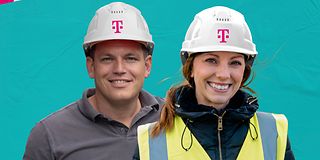 Zwei Personen mit Arbeitskleidung und magenta-farbenen Bauarbeiter-Helm