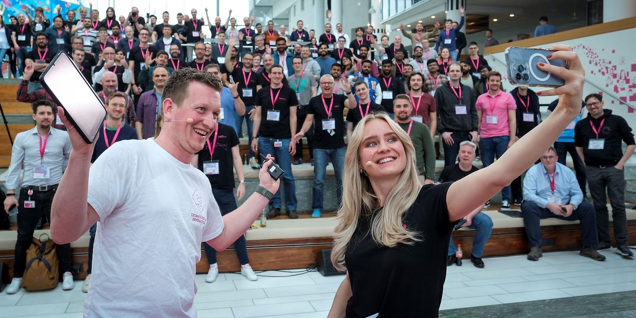 2 presenters stand in front of a group and take a selfie