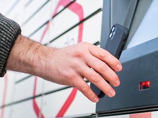 Eine Frau holt ihr Paket aus dem Schließfach der Paketstation.