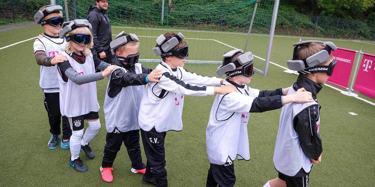Kinder mit einer Blindenbrille bilden eine Kette.