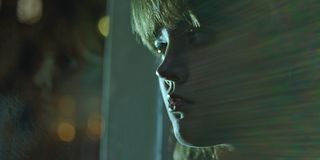 Young woman, depicted from the side, looking out the window, light reflection across the picture.