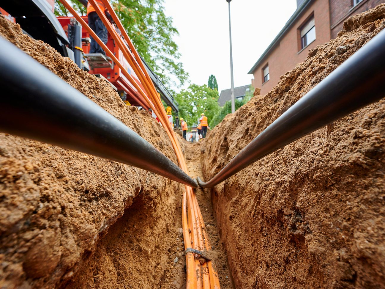 Ein schmaler und tiefer Graben im Gehweg, in dem Leerrohre verlegt werden.