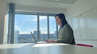 Volontärin sitzt am Schreibtisch mit ihrem Laptop und führt ein virtuelles Interview