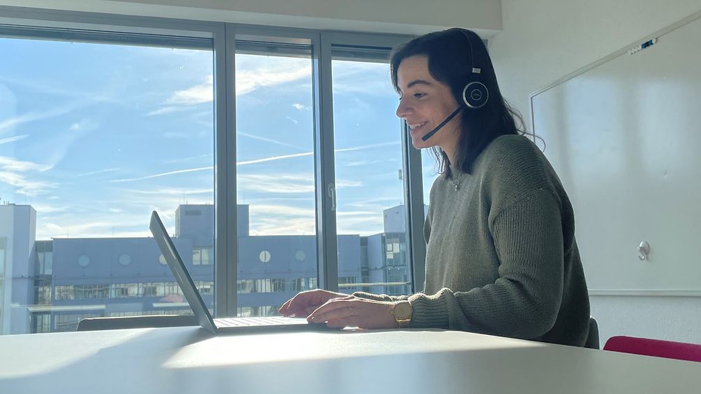  Volunteer sits at the desk with her laptop and conducts a virtual interview