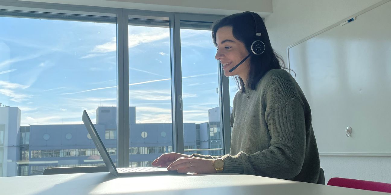  Volunteer sits at the desk with her laptop and conducts a virtual interview