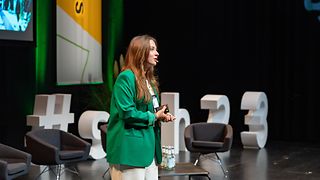 Close-up of a young woman giving a presentation at a conference.