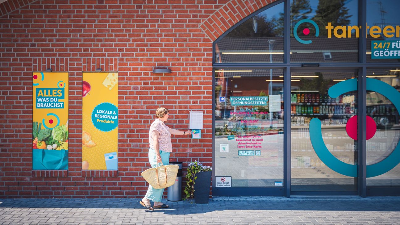Woman with shopping bag opens supermarket door with access card.