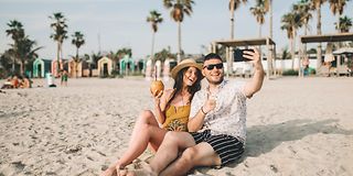 Paar mit Smartphone am Strand