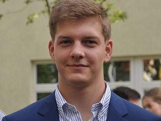 Autor Tim Stark. Ein junger Mann, draußen vor einem Gebäude