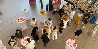 People stand at bar tables in a foyer