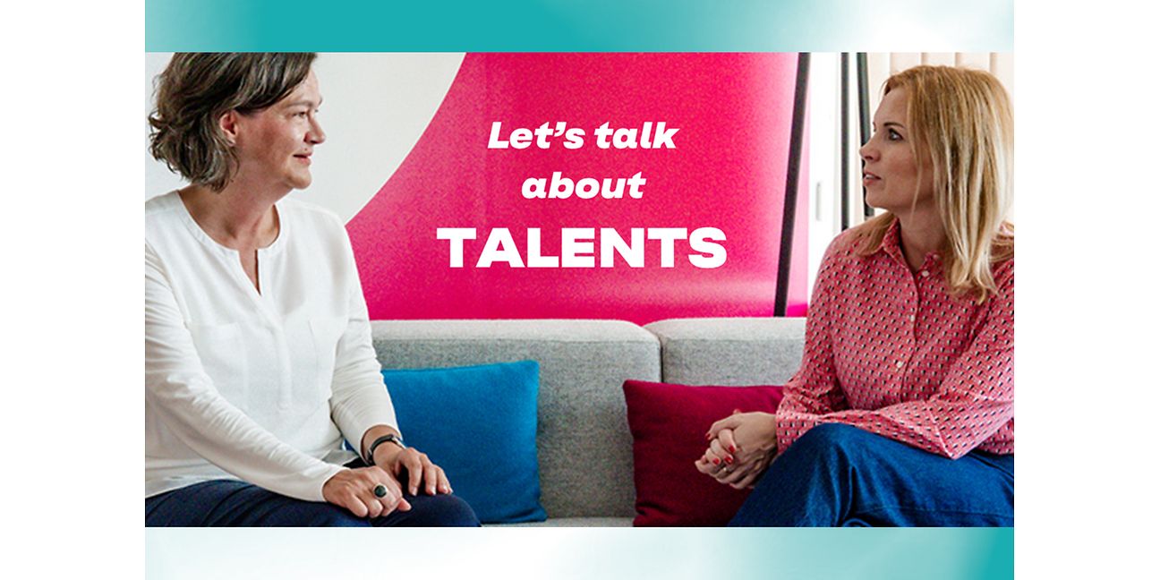 Bild von zwei Managerinnen, die auf einem Sofa sitzen und diskutieren.