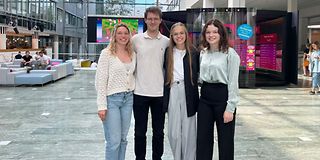 Four young people smile into the camera