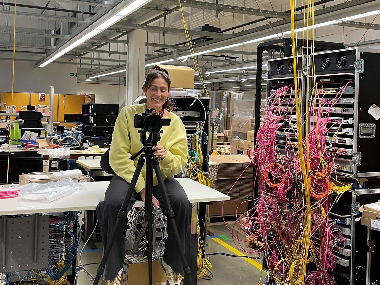Eine Frau sitzt in einem Technikraum hinter der Kamera