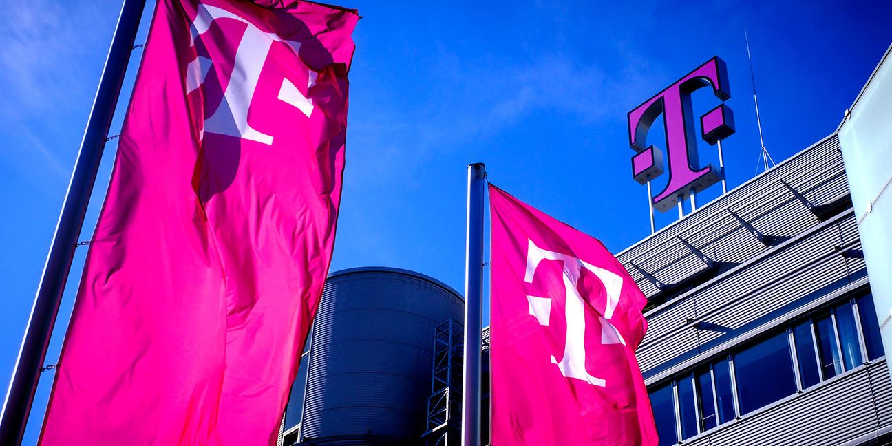 Blick auf ein Telekom Gebäude mit großem Telekom Logo und magentafarbenen Fahnen vor blauem Himmel